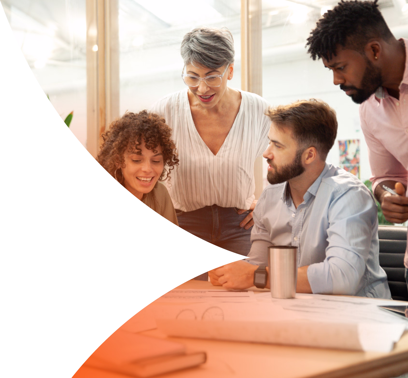 Four diverse coworkers collaborating over documents at a table in a modern office.