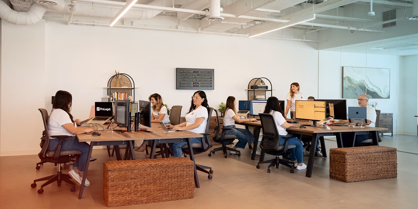 Office with employees working on computers and collaborating in a modern, open workspace.