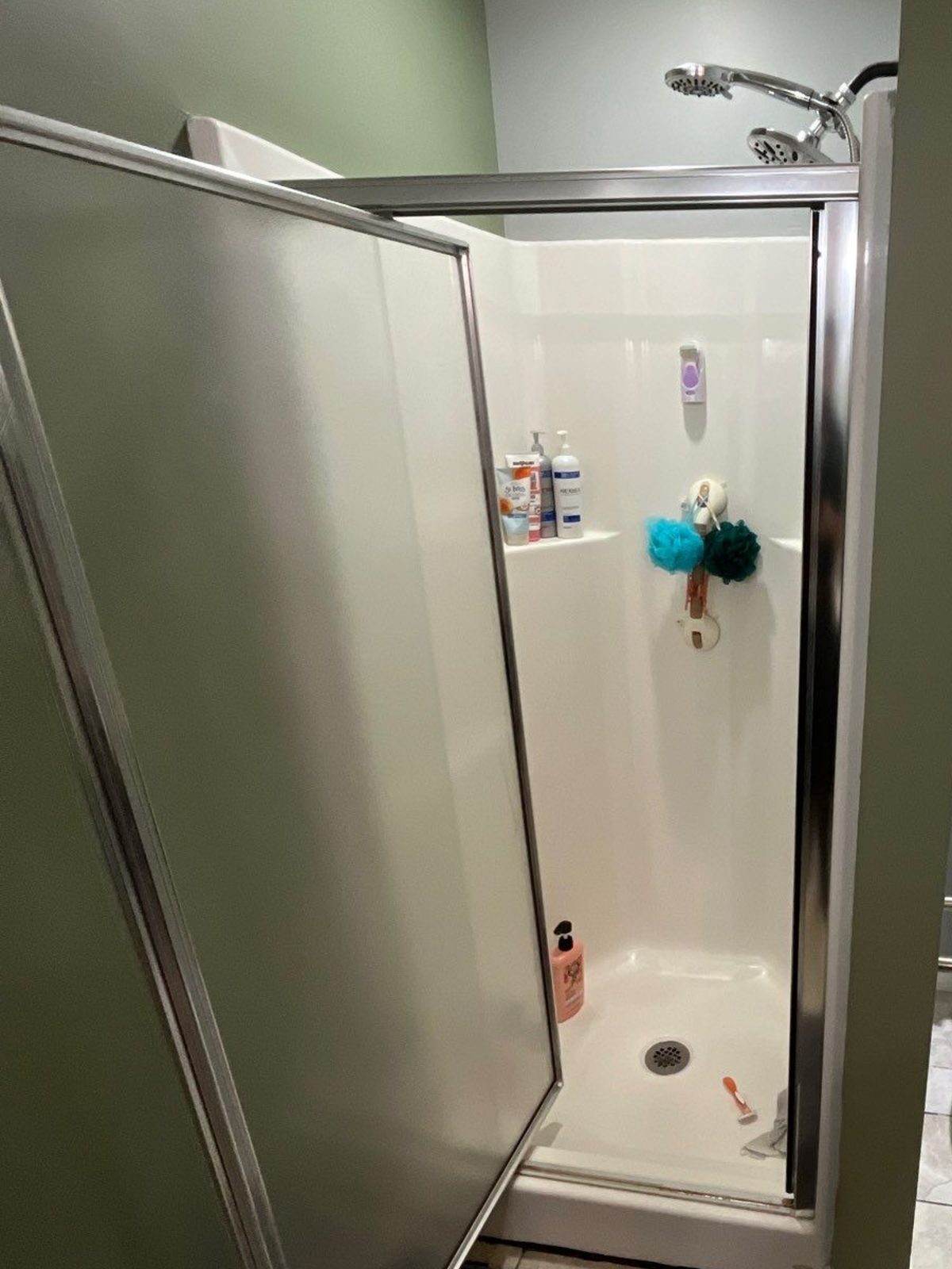 Fiberglass shower stall with an open hinged glass door before it was replaced with a bathtub in Baxter, TN
