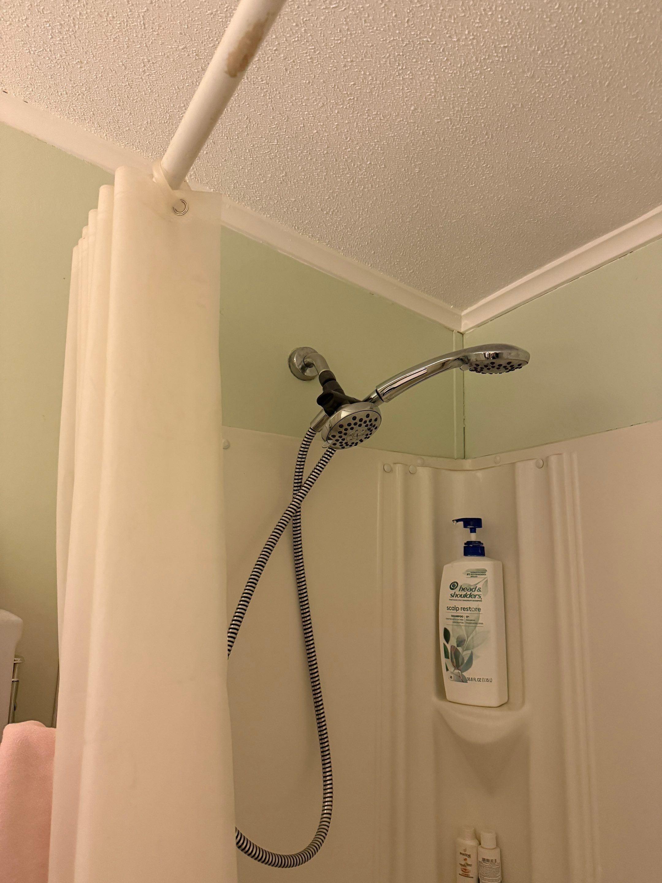 Old cream fiberglass surround with a molded soap dish, a stained curtain rod and a handheld shower on a hose before tub-to-shower conversion in Antioch, TN