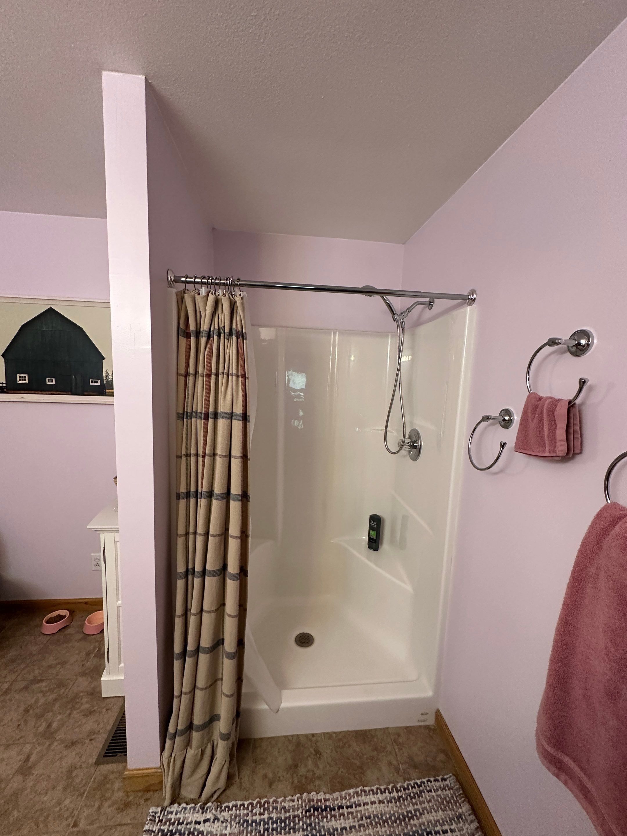 Old white fiberglass shower stall with a molded corner ledge, chrome rod and fabric curtain under a sloped ceiling before shower replacement in Celina, TN