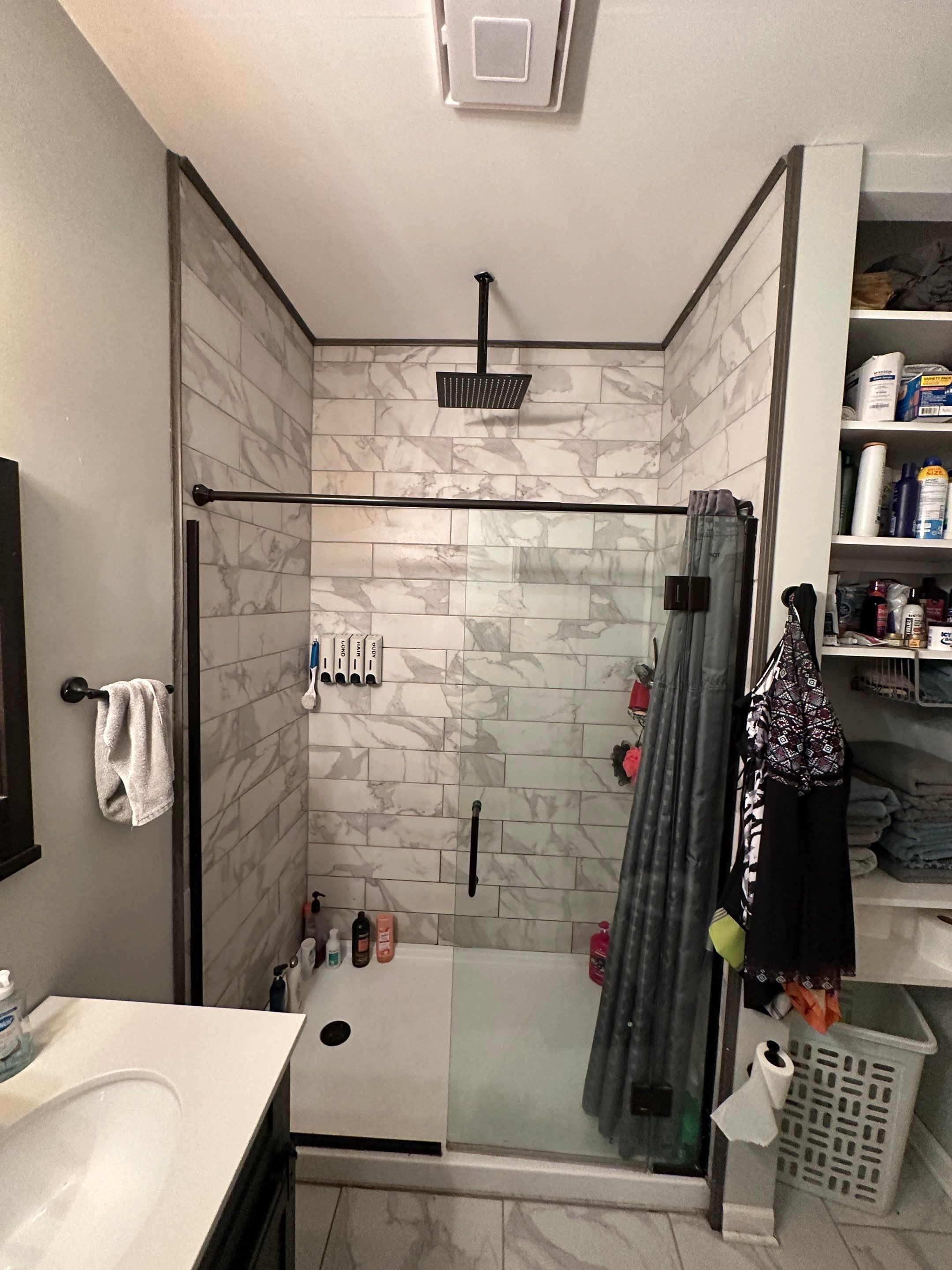 Tiled walk-in shower with grout lines, a ceiling rain head, a fixed glass panel and a fabric curtain before shower replacement in Bell Buckle, TN