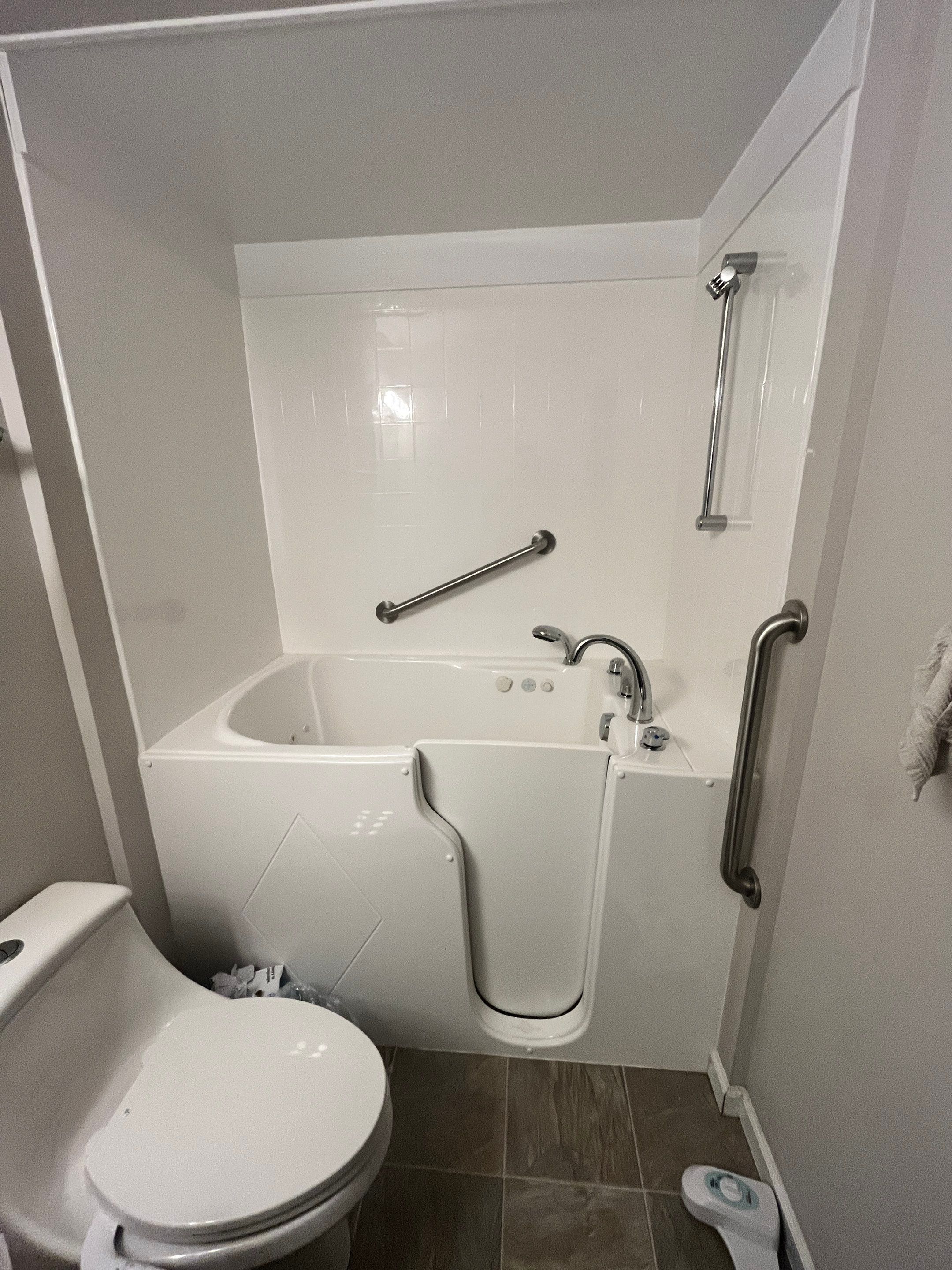 White walk-in bathtub with a side door, tile-look wall surround, grab bars and a slide-bar shower before tub-to-shower conversion in Manchester, TN