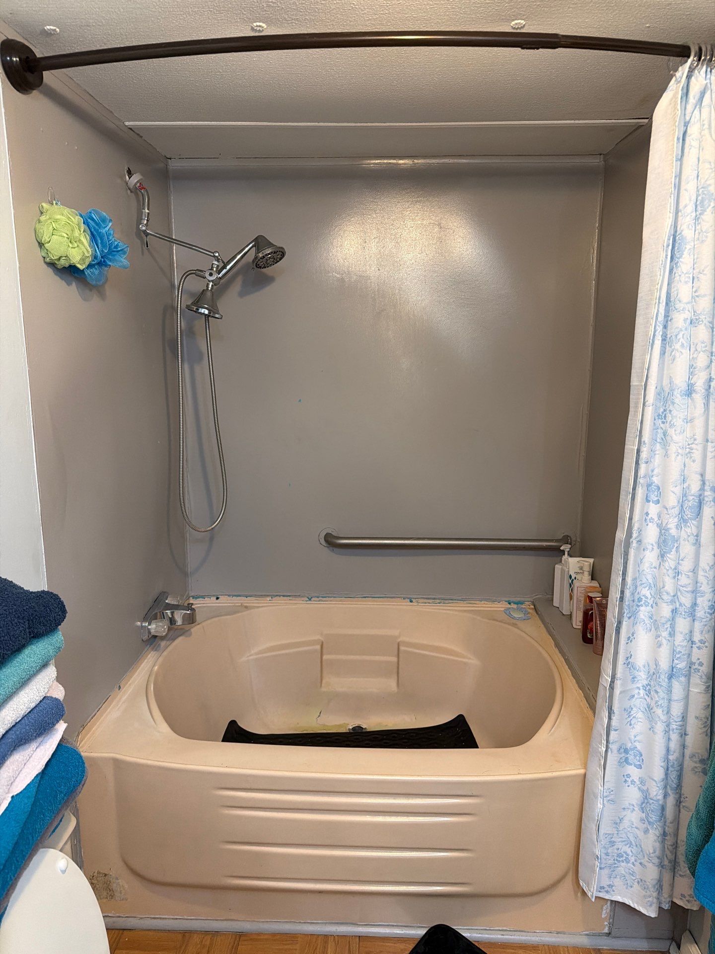 Almond garden-style soaking tub with gray painted surround, curved curtain rod and an old grab bar before tub-to-shower conversion in Estill Springs, TN
