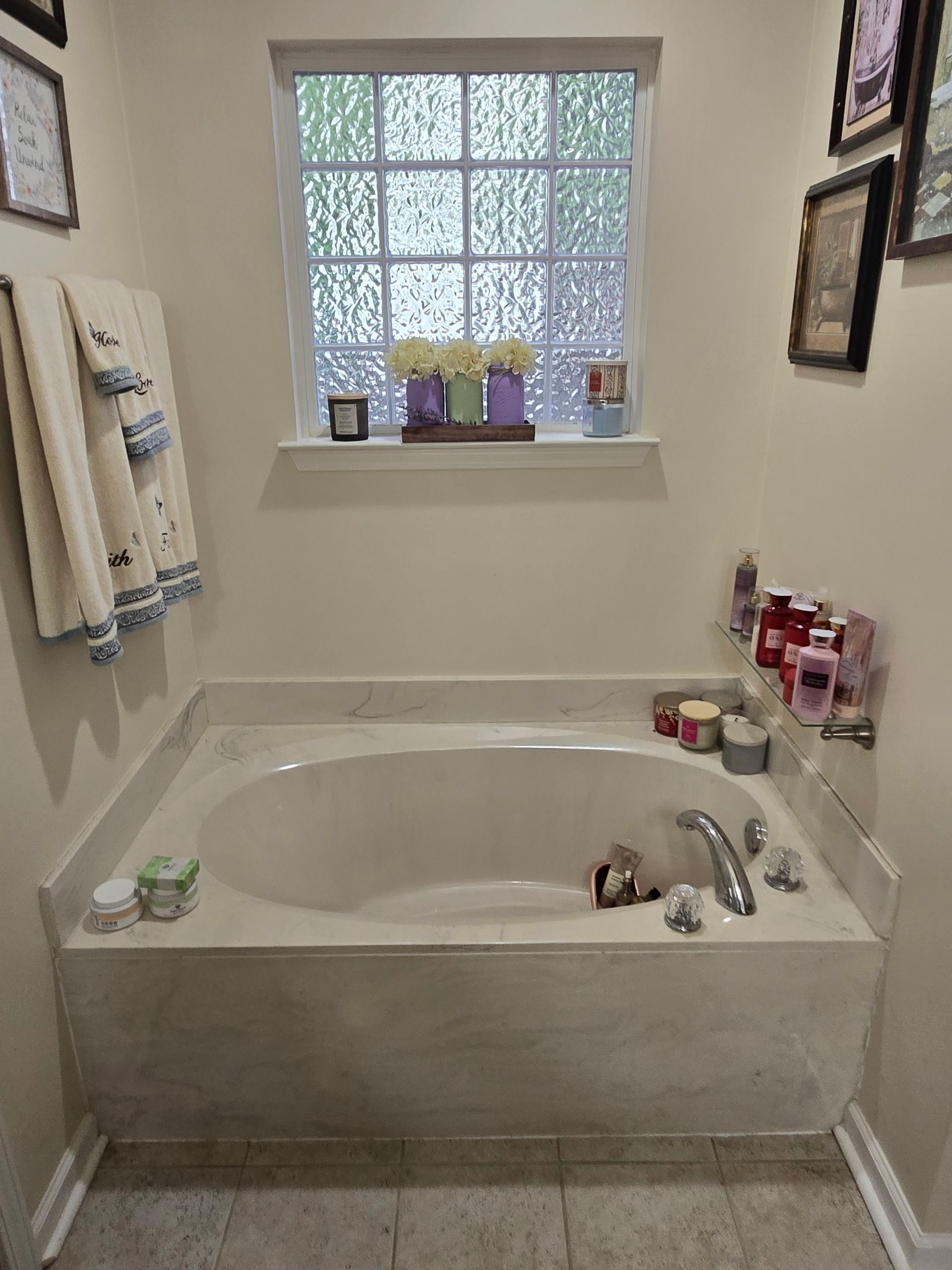 Drop-in garden soaking tub with a cultured marble deck under a glass block window before tub-to-shower conversion in Fairview, TN