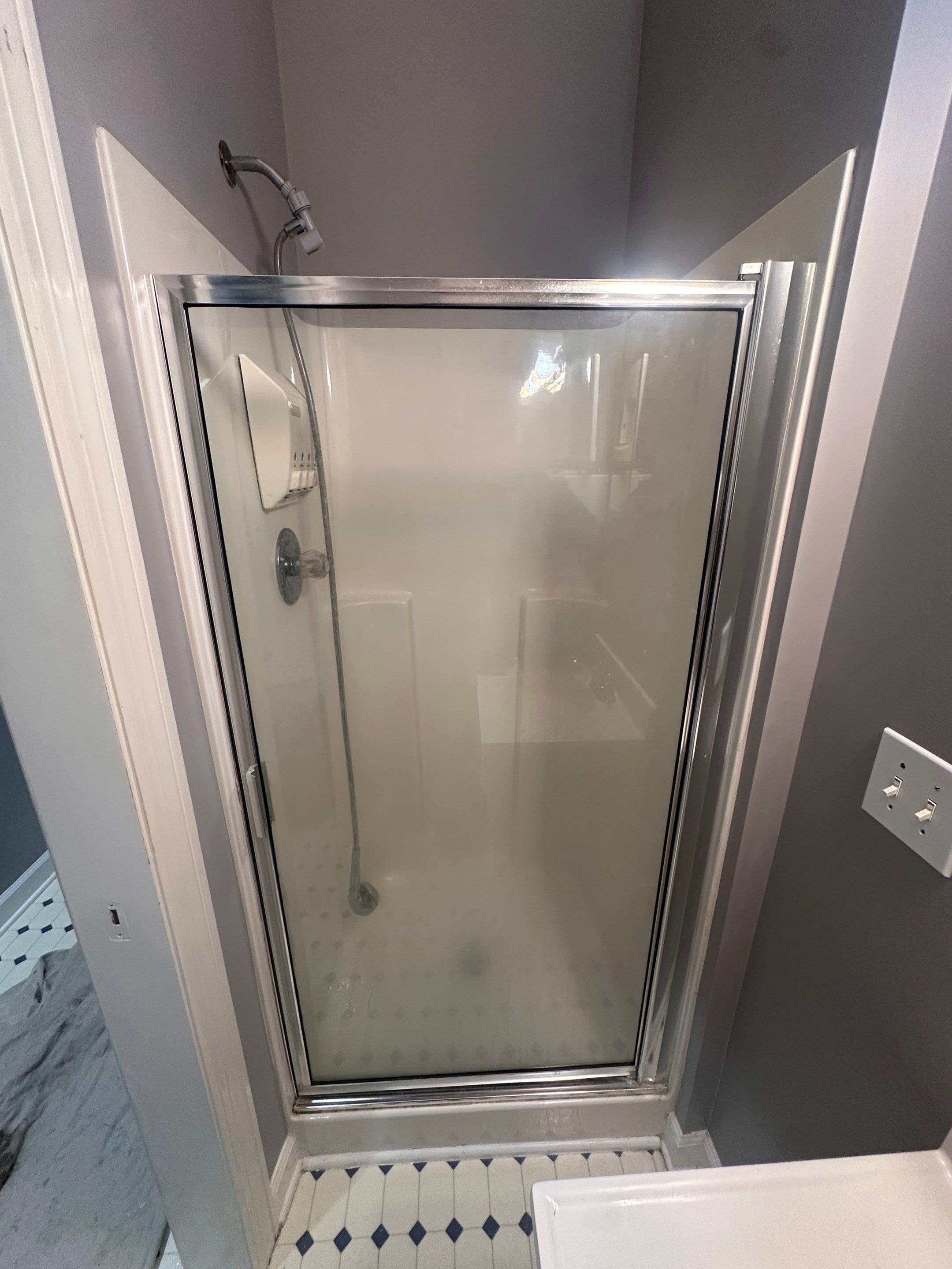 Old white fiberglass shower stall with a framed frosted-glass door and chrome trim before replacement in Nashville, TN