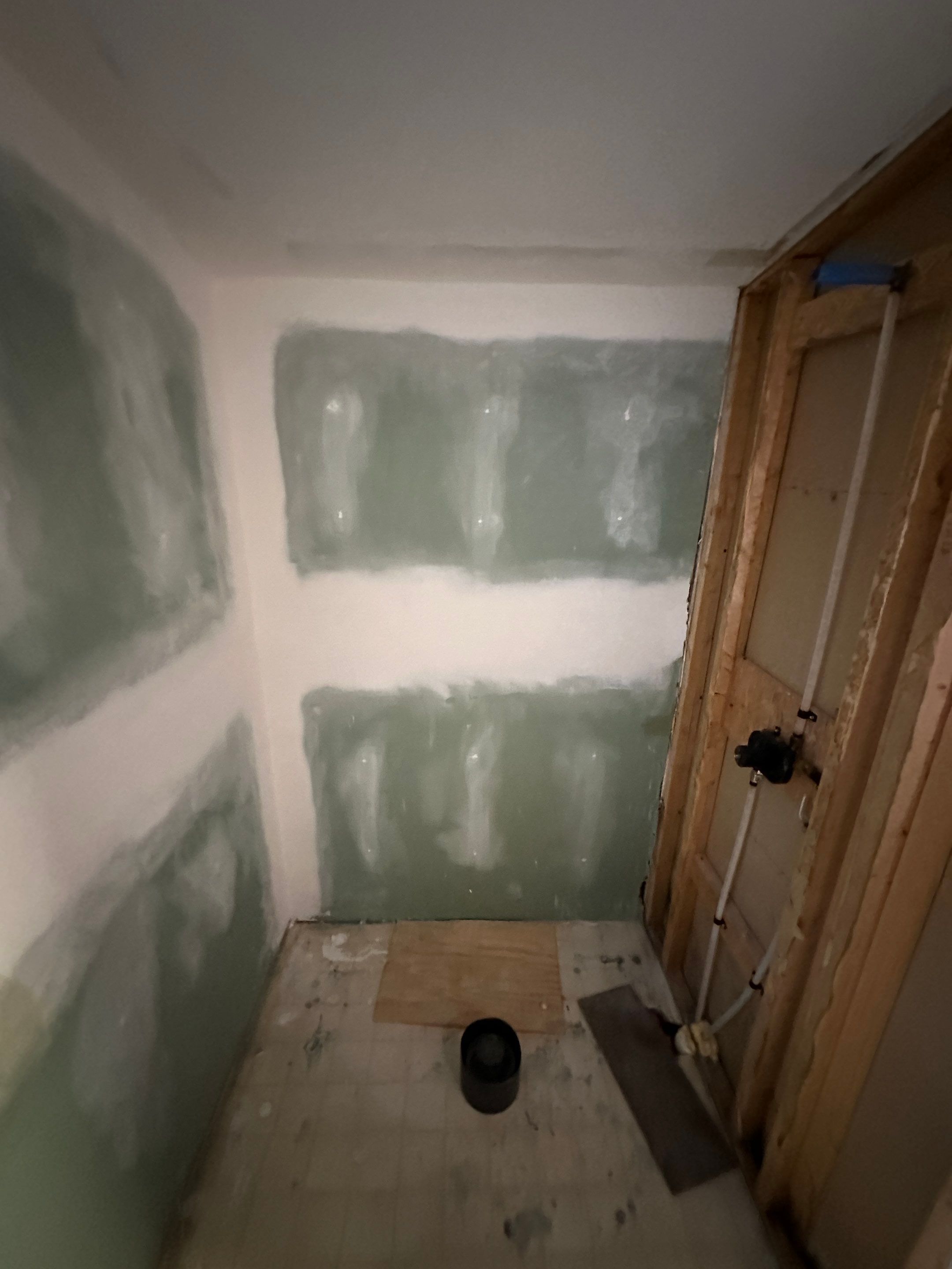 Empty shower space with green moisture-resistant drywall, open framing and a bare drain pipe on a subfloor before shower installation in Pleasant View, TN