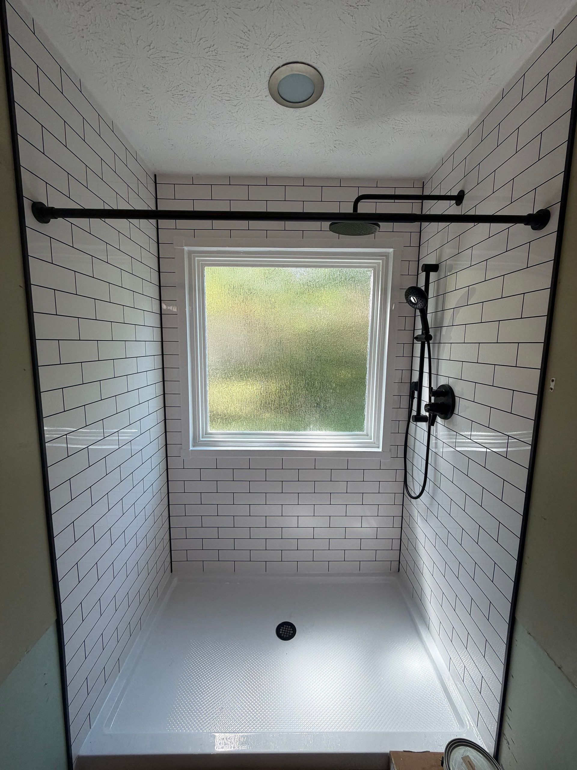 After: new walk-in shower with white subway tile and black fixtures