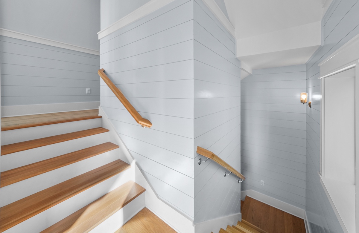 Beach house staircase with shiplap walls, wood steps, and natural light