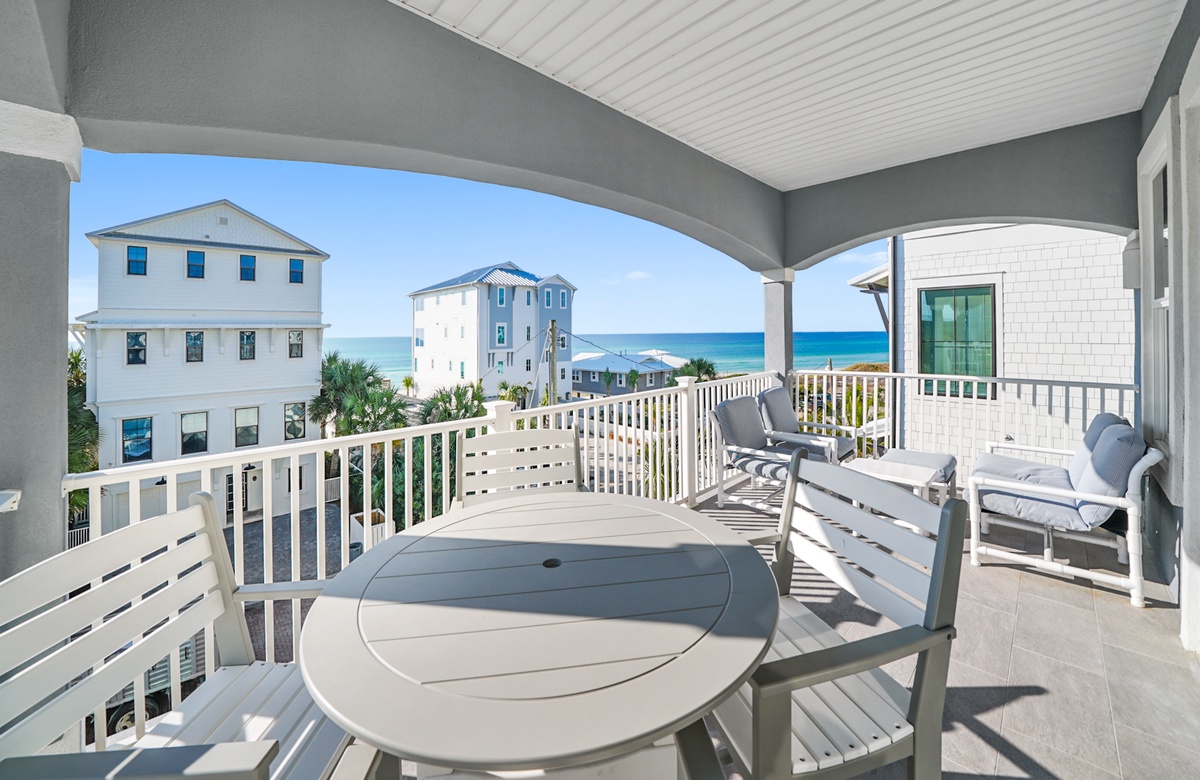 Covered beach house balcony with outdoor seating and Gulf water views