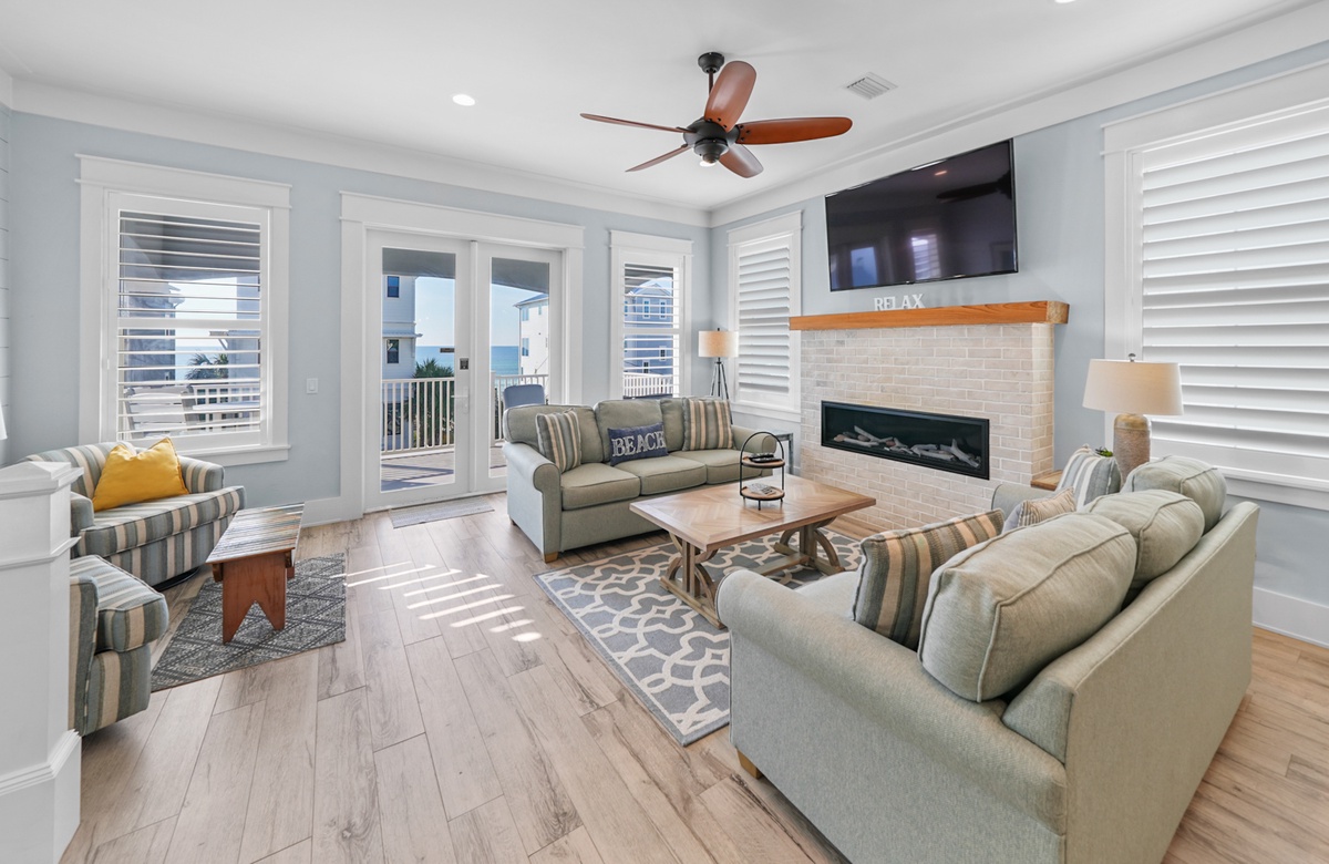 Coastal living room with fireplace, sofas, and balcony overlooking the ocean