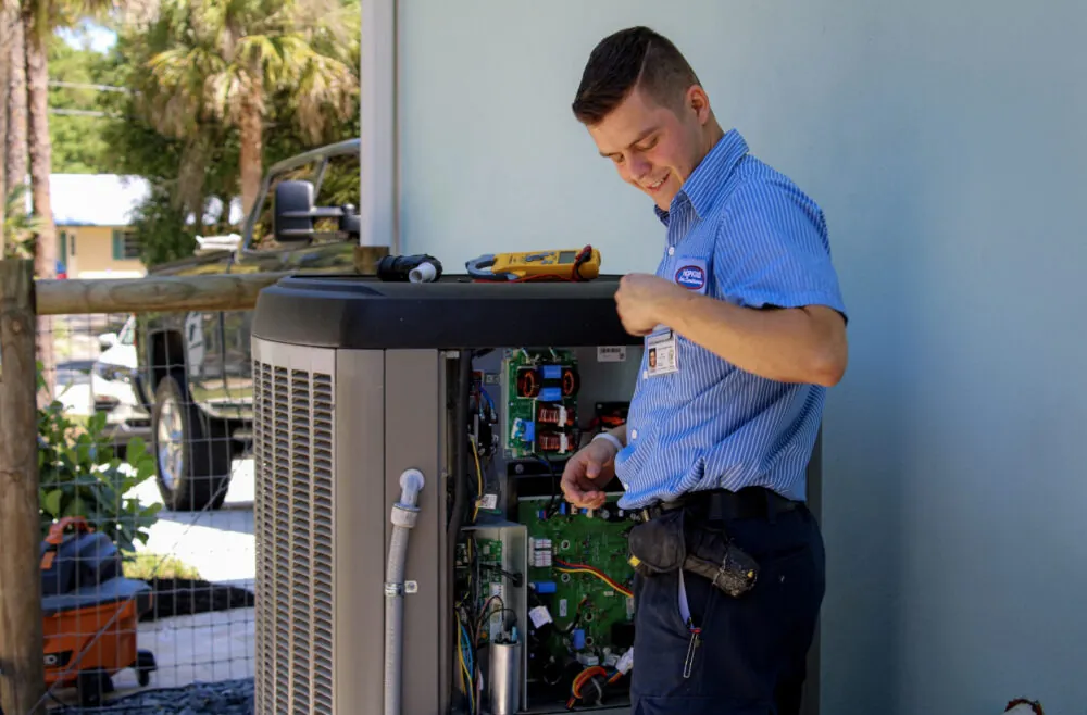 A technician repairing an outdoor HVAC unit