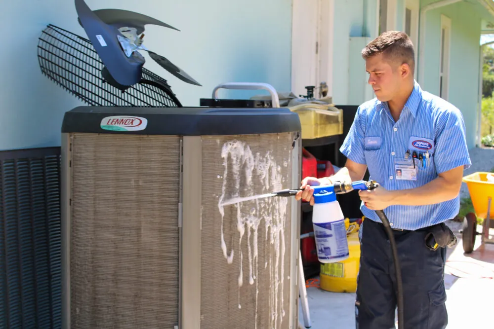 HVAC technician cleaning an outdoor AC unit