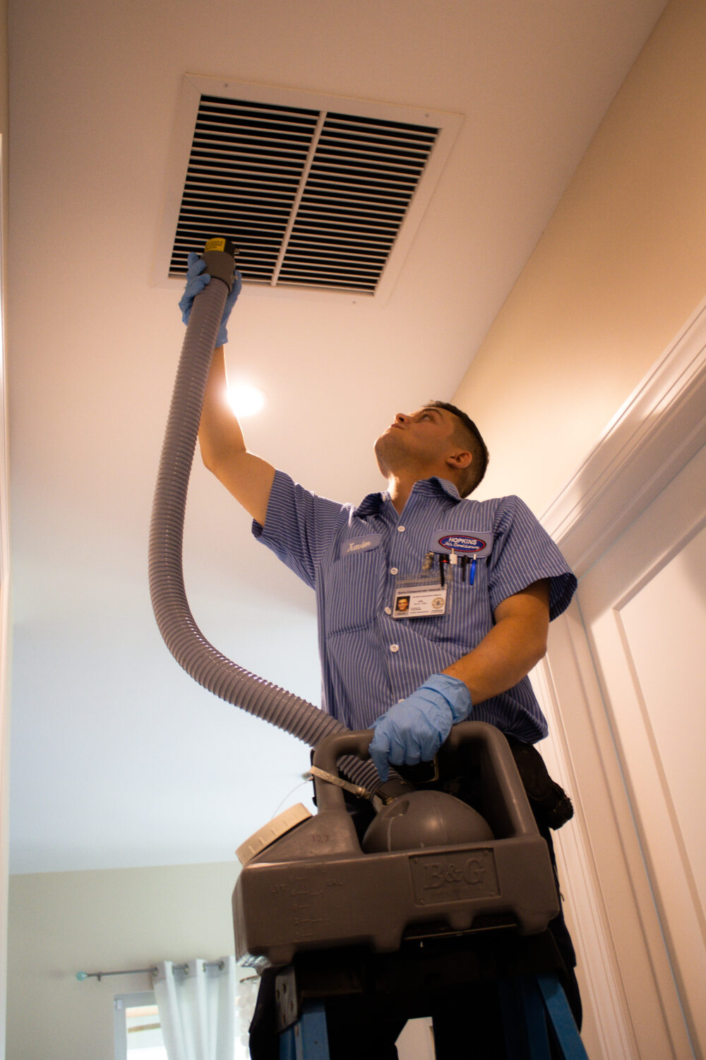 HVAC technician cleaning air duct in a ceiling