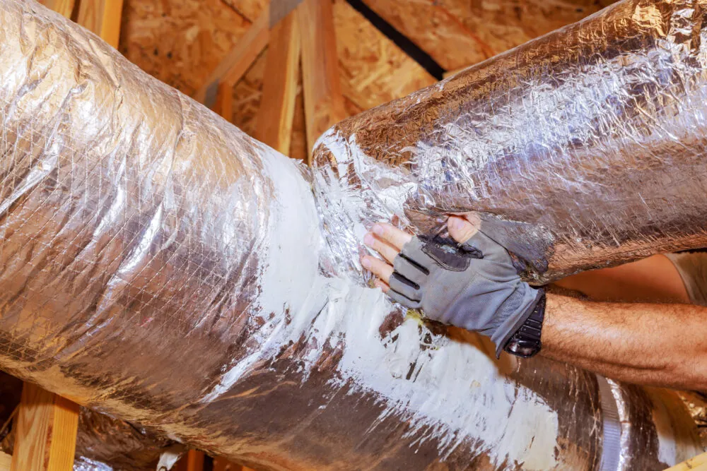 A technician installing a new HVAC ventilation system's ducts
