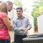 Technician explaining AC service to homeowners.