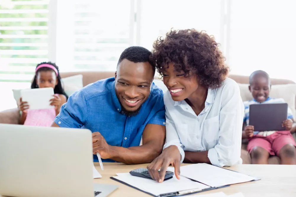 couple looking at a laptop with a clipboard and calculator