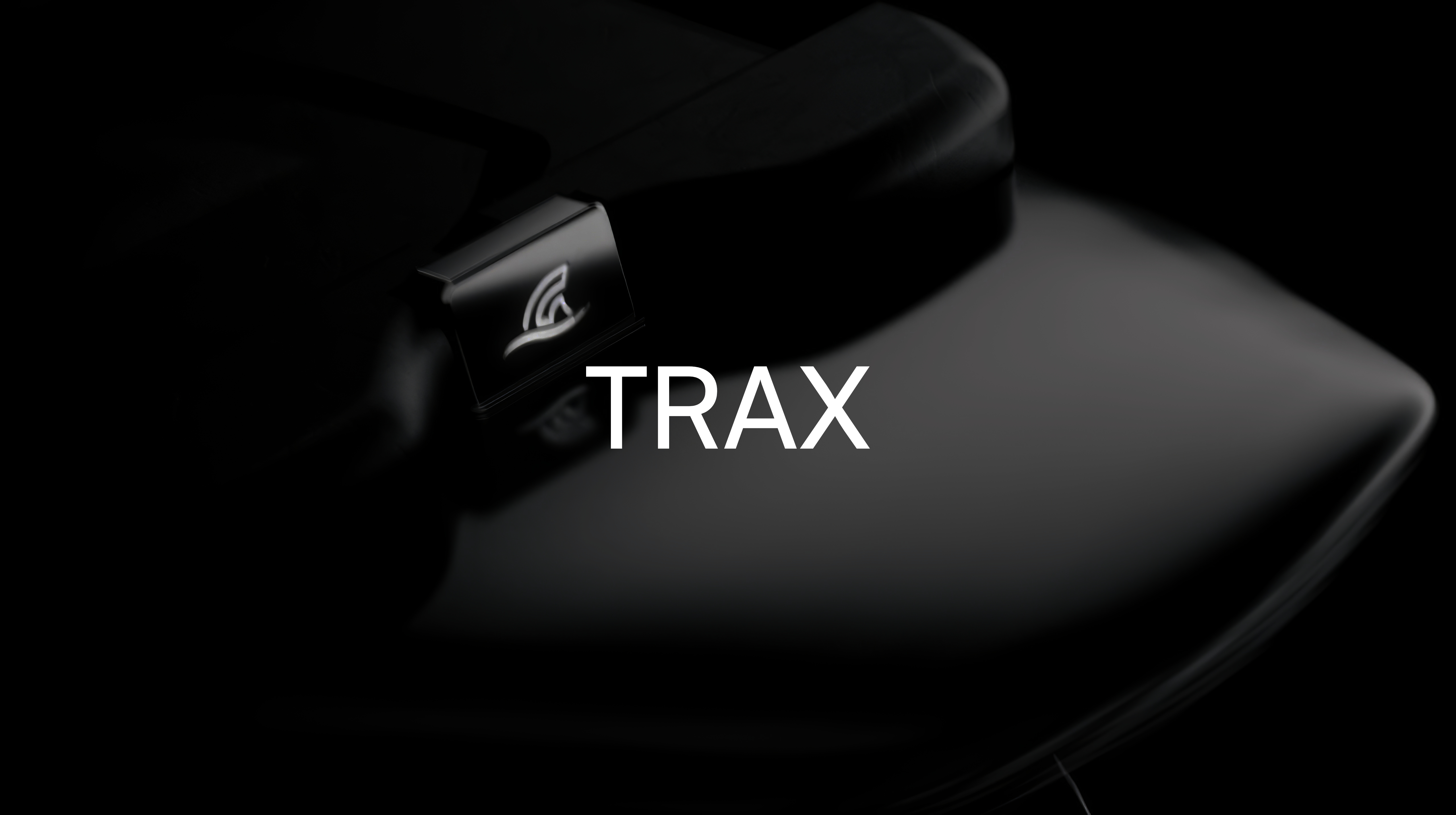 Close-up of a sleek black device with a small illuminated logo and the text TRAX centered.