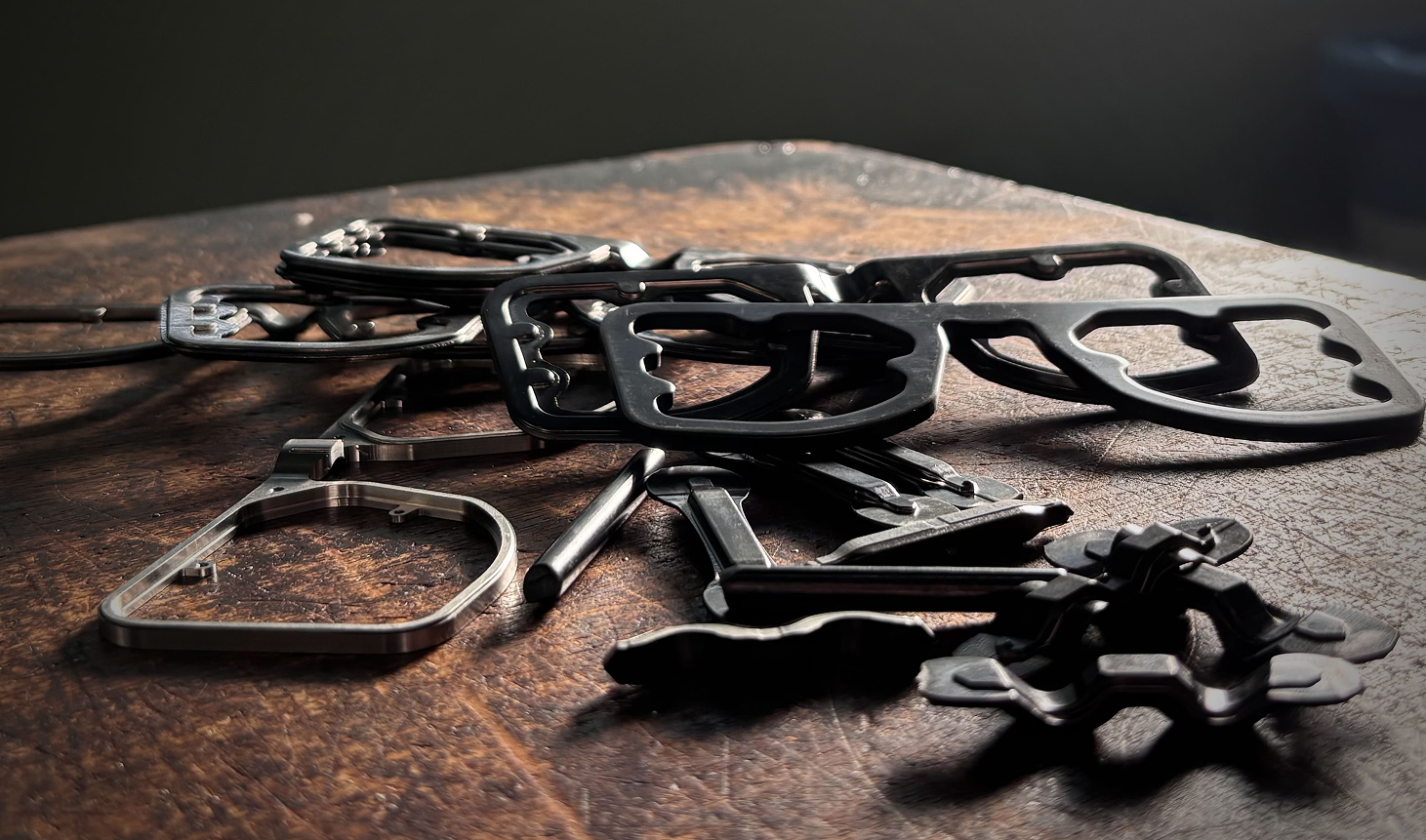 A collection of raw, milled DRK frame components on a wooden workbench, showcasing the solid, sculptural forms before they are hand-finished.