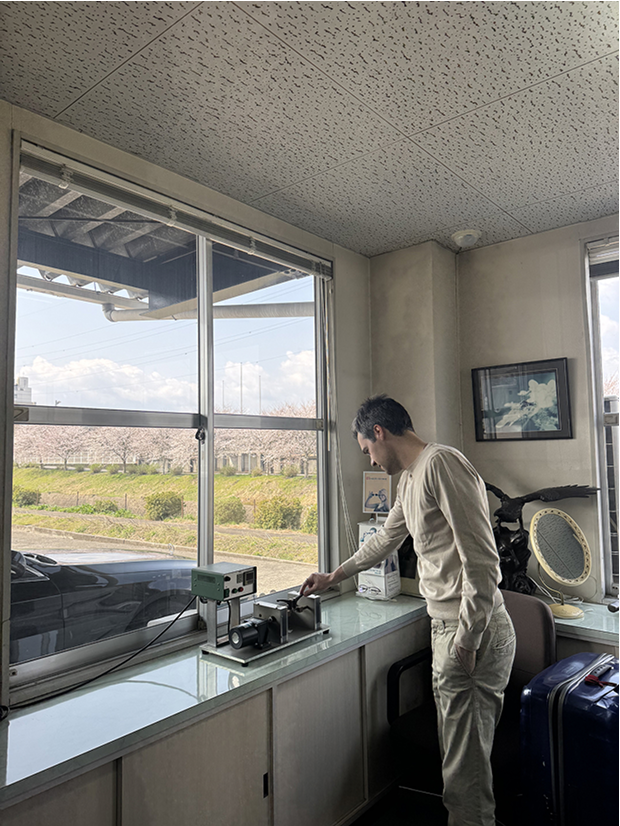 DRK's founder personally inspecting precision machinery at the Sabae, Japan workshop, overseeing the creation of the masterpieces, with a view of cherry blossoms outside the window.