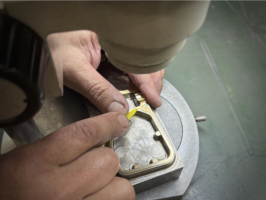 A macro, close-up view of an artisan's hands meticulously hand-finishing the brass pressing mold for a DRK frame, a process requiring extreme precision.