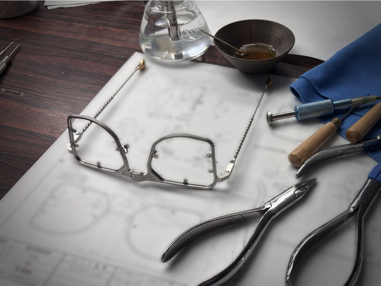 The final assembly workbench for a DRK masterpiece: a frame rests on its technical schematics, surrounded by precision hand-tools, pliers, and custom-finishing liquids.