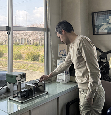DRK's founder personally inspecting precision machinery at the Sabae, Japan workshop, overseeing the creation of the masterpieces, with a view of cherry blossoms outside the window.