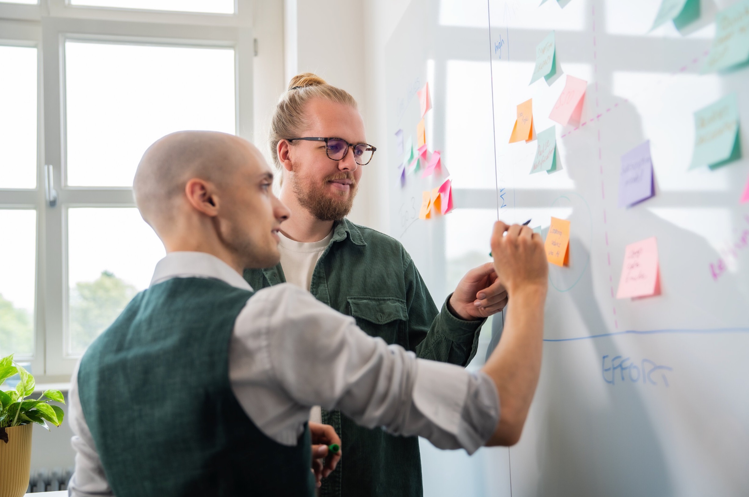 Two people writing on a whiteboard in a workshop context