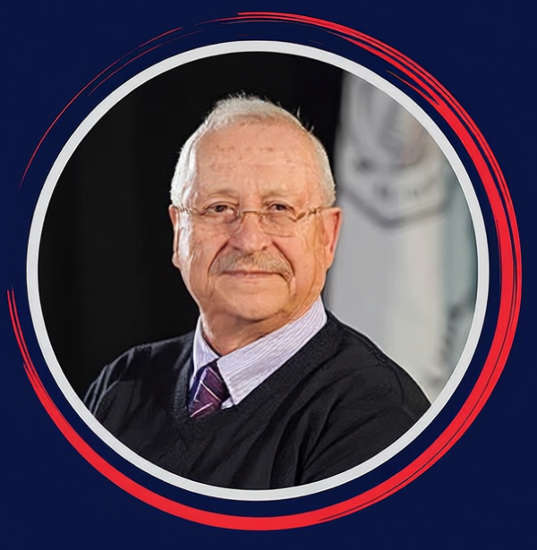 Portrait of an older man with glasses and a mustache wearing a striped tie and dark sweater, framed by a circular red and white border on a navy background.
