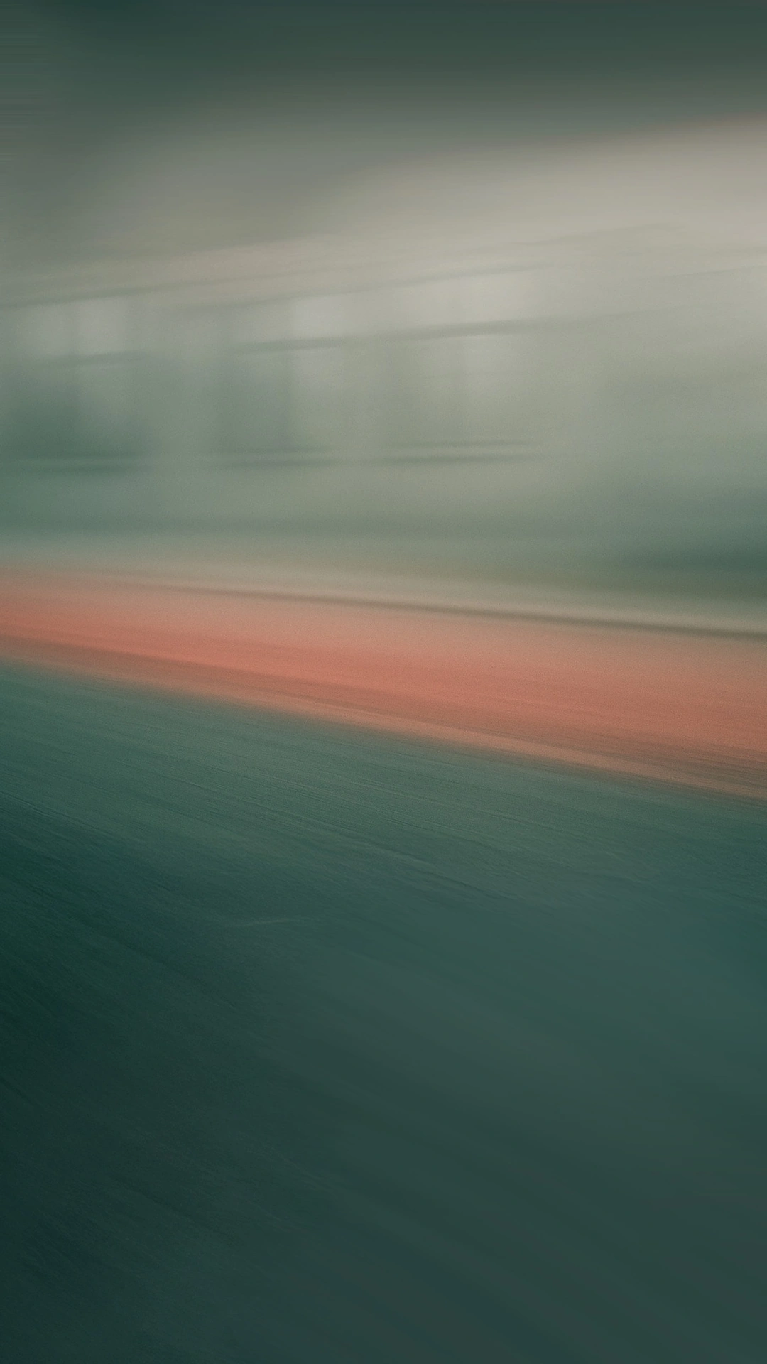 Blurred view of a green and orange surface with faint rectangular shapes in the background.