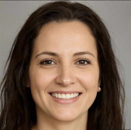 Smiling woman with long dark hair and brown eyes against a plain background.