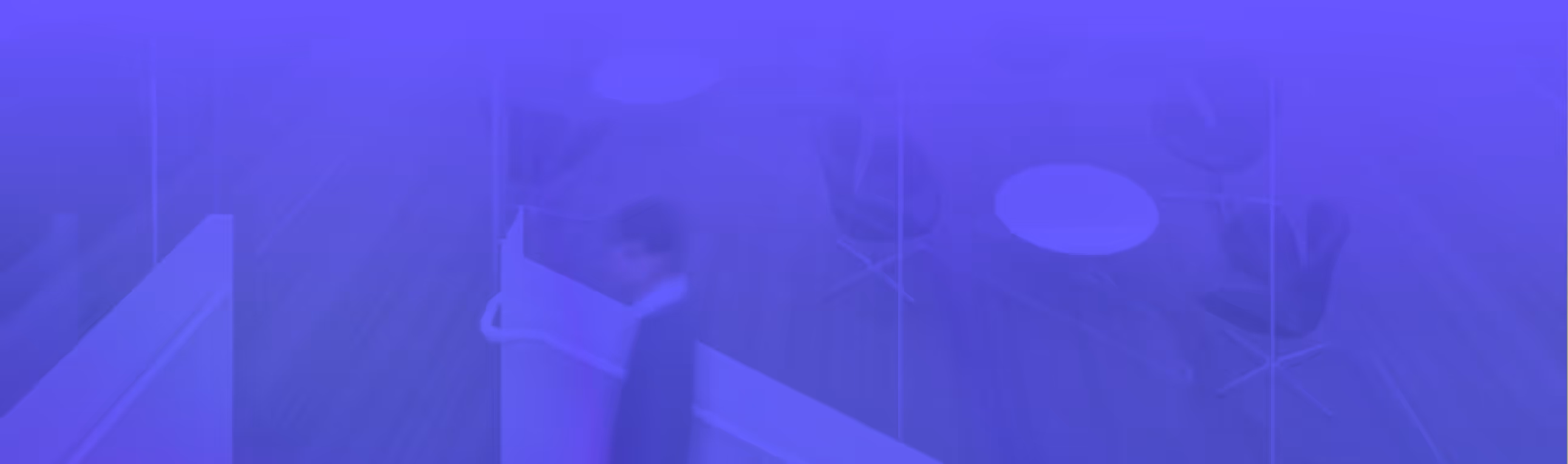 Blurred office scene with a person walking past desks and chairs.