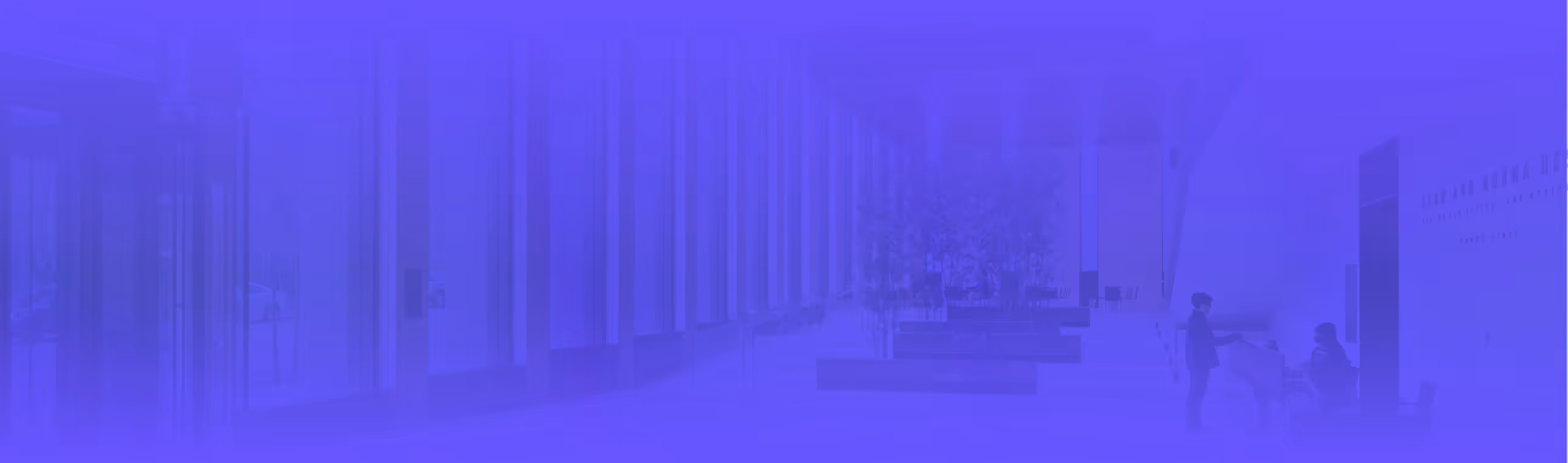 Corporate lobby with tall glass windows, benches, trees, and two people interacting indoors near a wall.