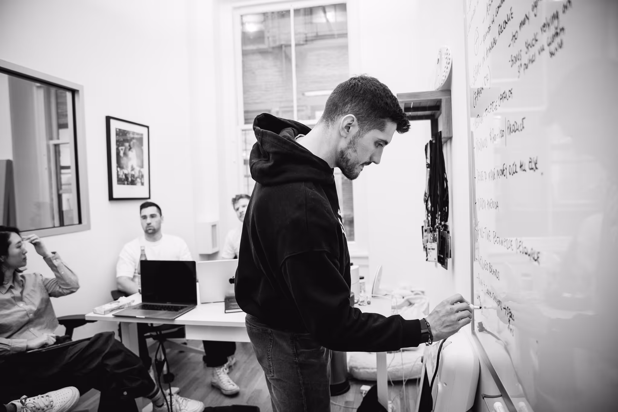 Ben is writing on a whiteboard in an office