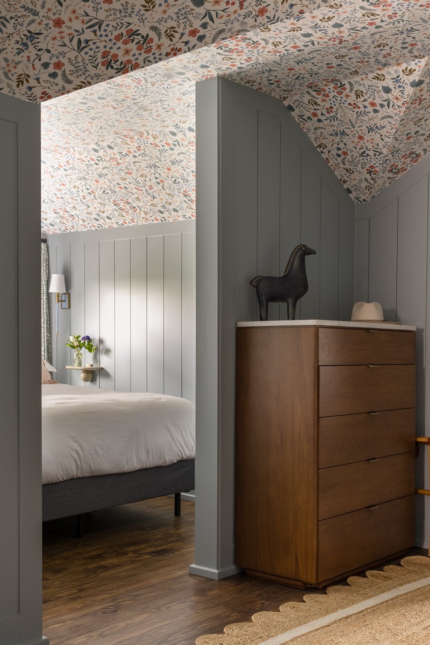 Queen bed and walnut dresser under the sloped loft ceiling, The Geny suite