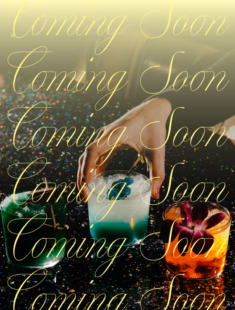 A hand with pink fingernails reaching for a blue-green cocktail with two other colorful cocktails, one green and one orange with a purple flower, on a dark glittery surface.