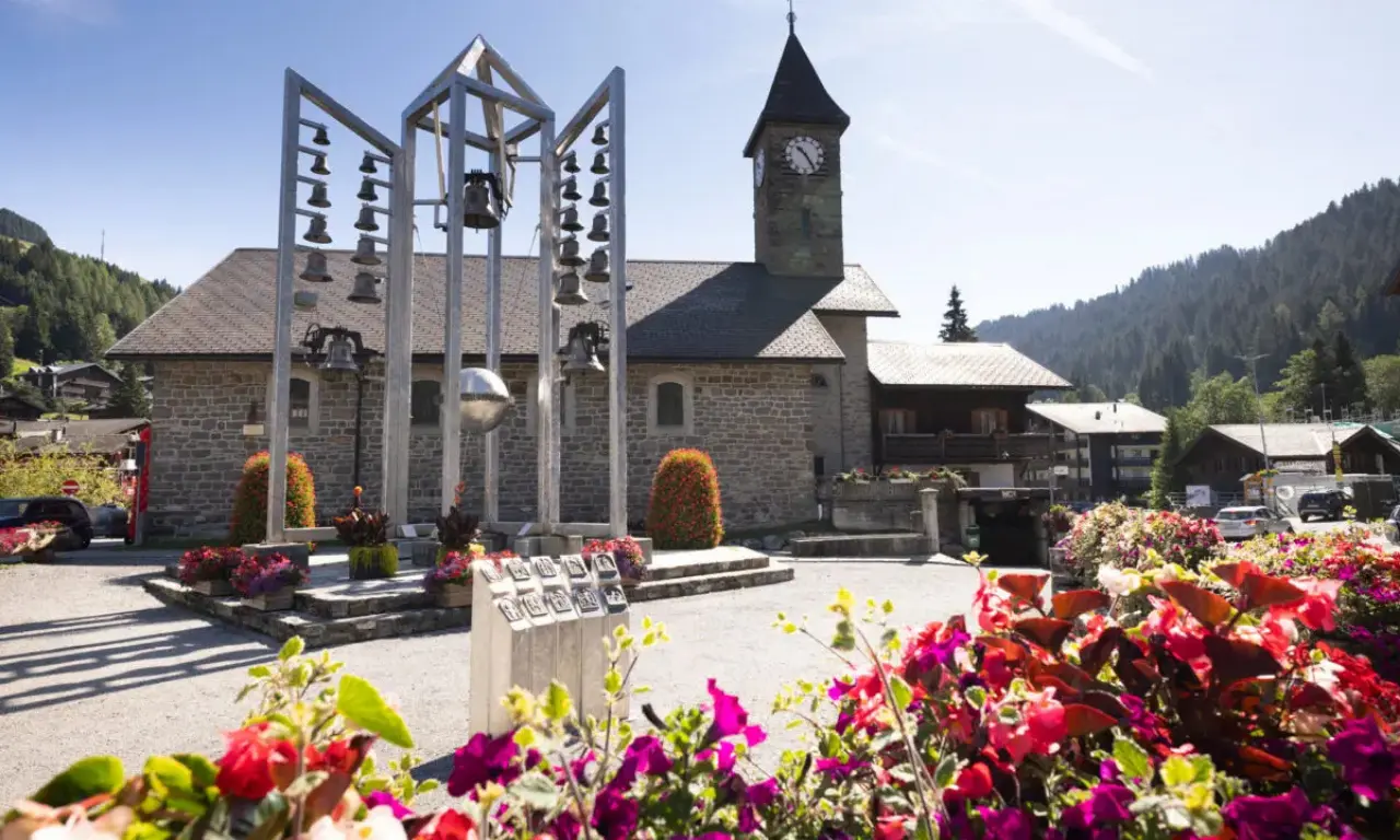 Vue du Carillon de Morgins et de l’église au cœur du village avec des fleurs en premier plan