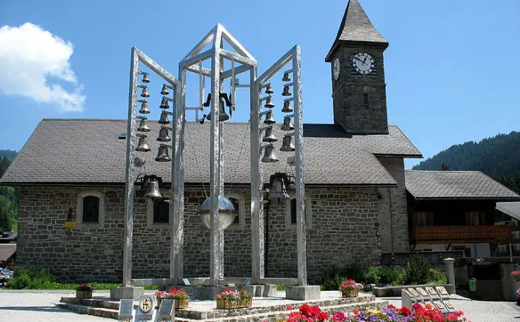 Le Carillon de Morgins devant l’église Saint-Théodule sous un ciel ensoleillé