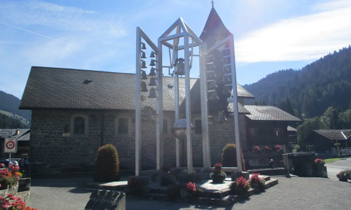 Le Carillon de Morgins devant l’église Saint-Théodule sous un ciel ensoleillé