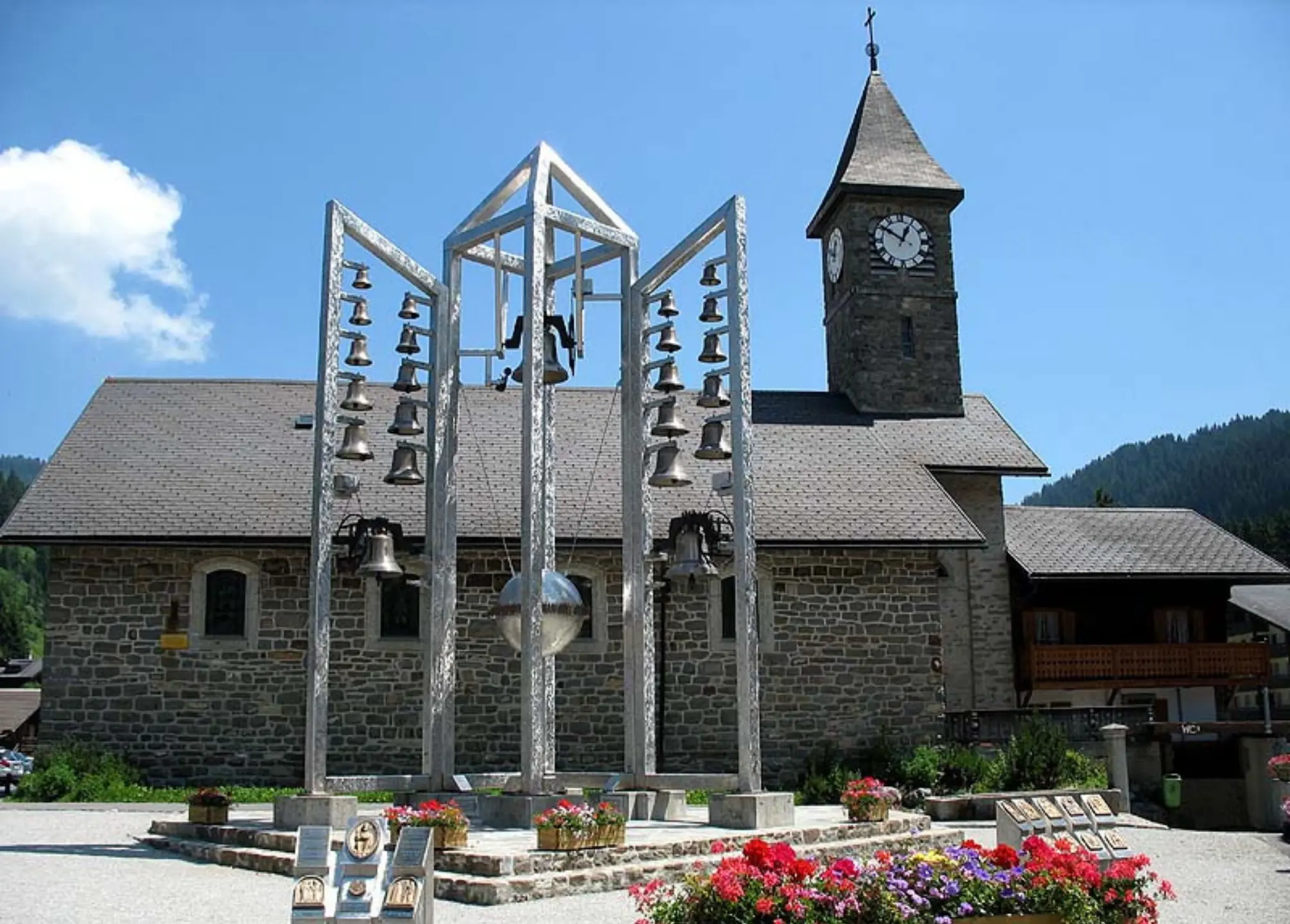 Le Carillon de Morgins devant l’église Saint-Théodule sous un ciel ensoleillé