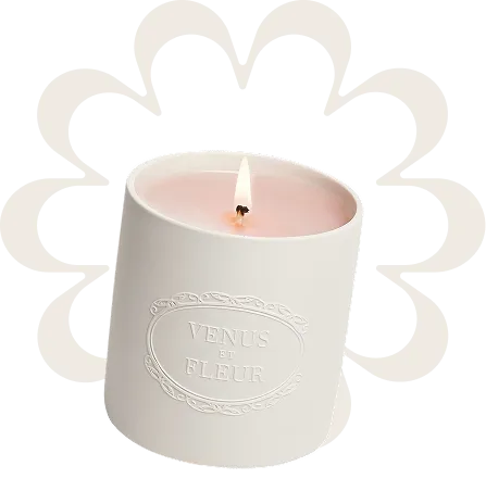 A white candle holder with a lit candle inside of it.