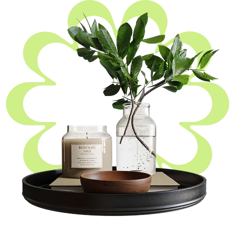 A vase with a plant and some candles on a tray.