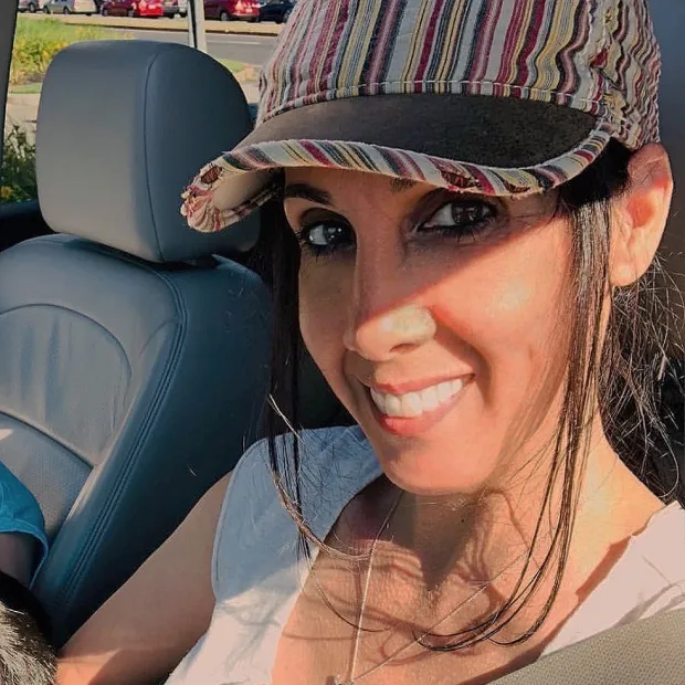 Smiling woman wearing a striped cap sitting in a car with a gray leather seat.