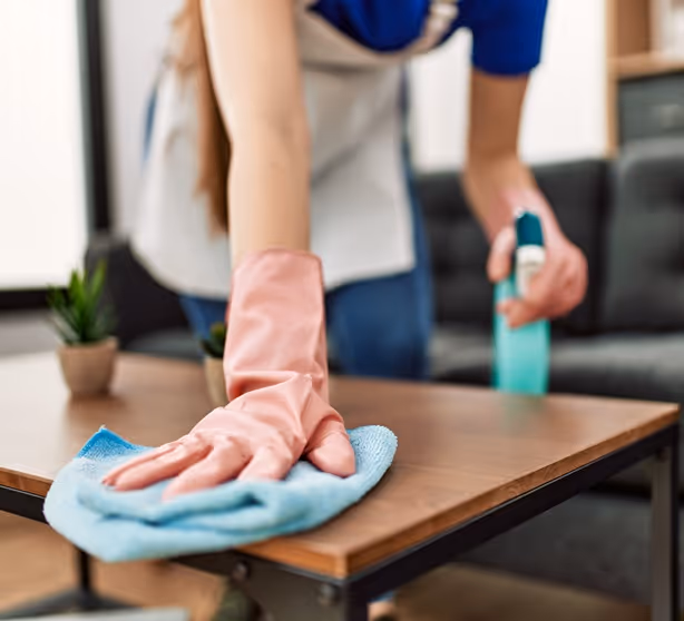 A woman cleaning a table with a blue cloth.