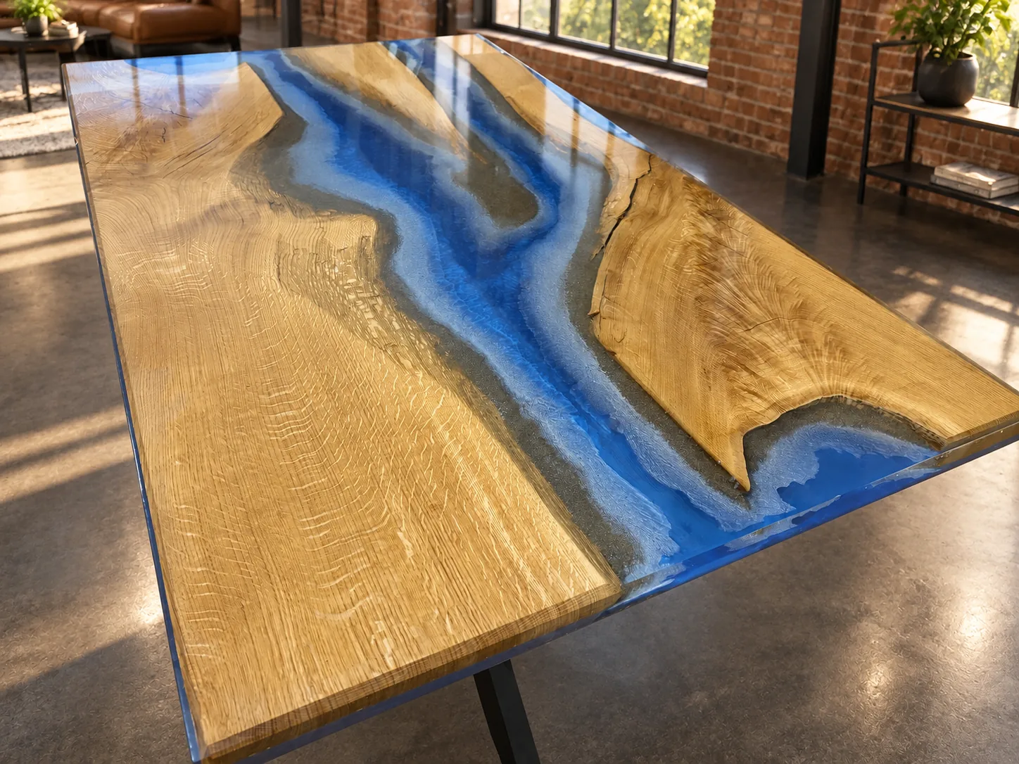 Tisch mit Oberfläche aus hellem Holz und blauem Epoxidharz, das wie ein Fluss in der Mitte des Tisches verläuft, in einem hellen Raum mit Backsteinwänden und großen Fenstern.