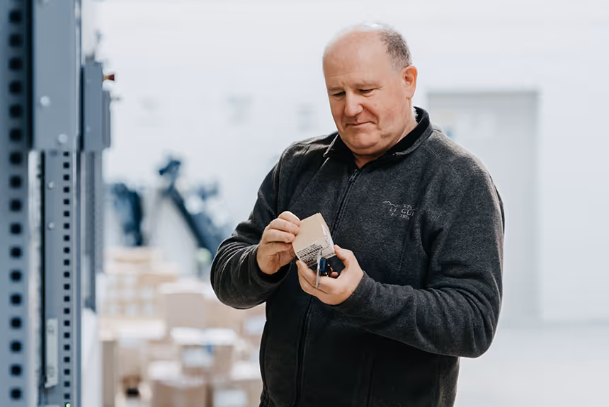 Mitarbeiter prüft ein Bauteil im Lager