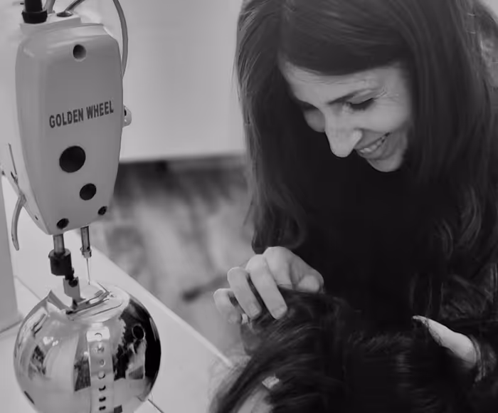 Une femme souriante regardant et touchant doucement la tête d'une autre personne près d'une machine à coudre Golden Wheel.