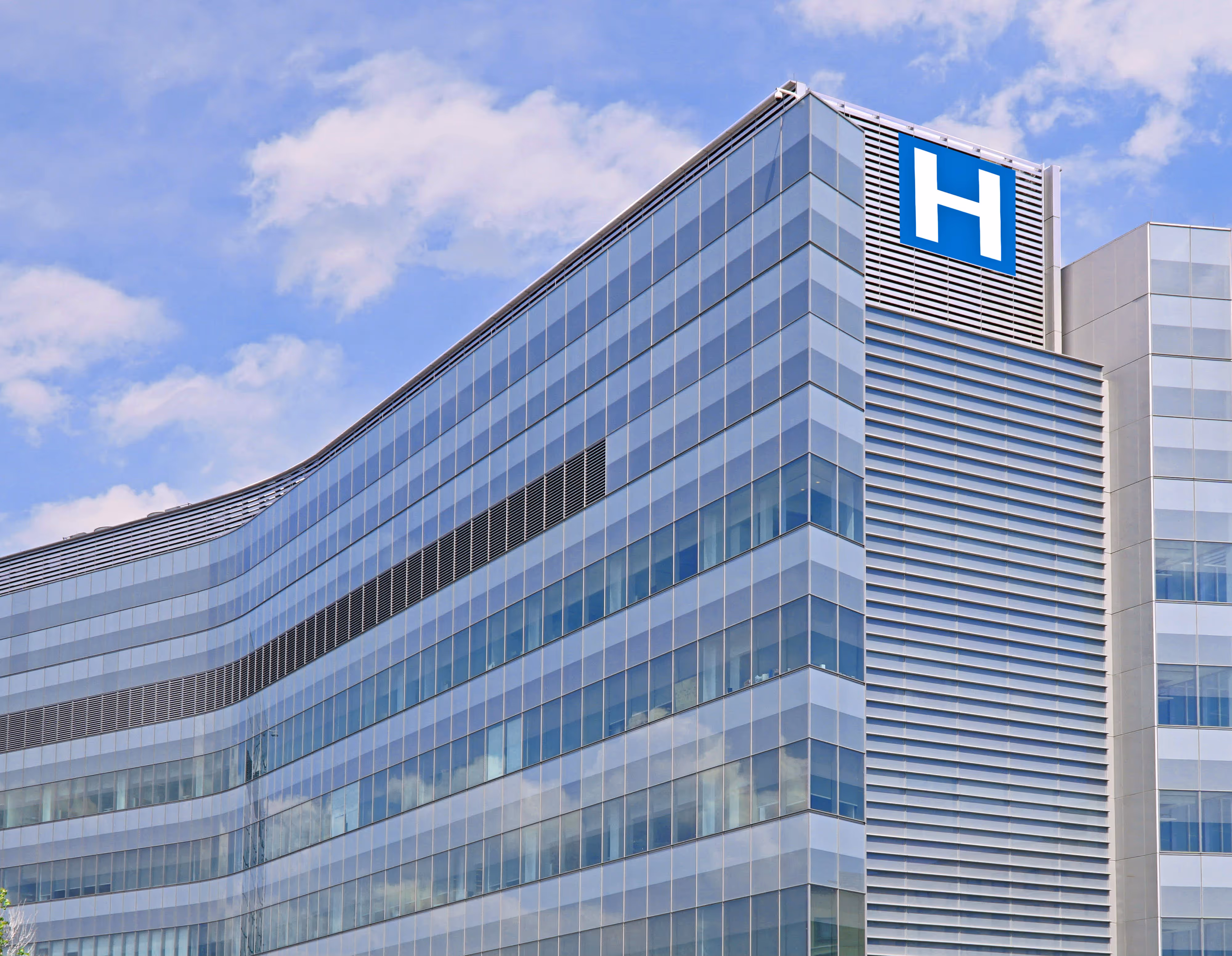 Modern hospital building exterior with medical signage, representing healthcare facilities and clinical environments.