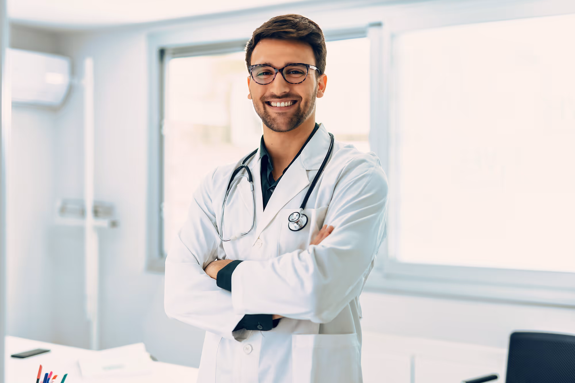 Smiling doctor standing confidently in a medical setting, representing qualified healthcare professionals.