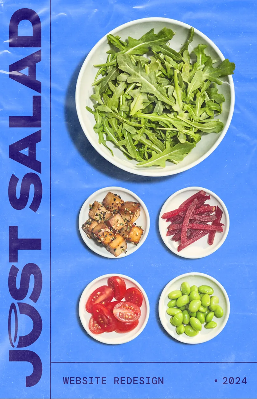 Overhead view of a bowl of fresh arugula with small bowls containing tofu cubes with sesame seeds, beet strips, halved cherry tomatoes, and green edamame beans on a blue background.